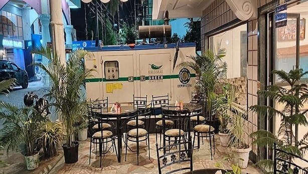 An outdoor seating area with a round table and chairs, surrounded by potted plants. - Hotel Sai's Village (Rahata)