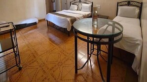 Una habitación de hotel con cama, una mesita redonda pequeña, un armario y un ventilador de techo.
