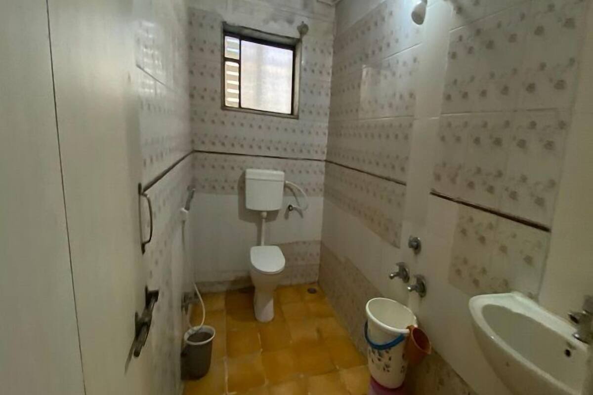 Een kleine badkamer met toilet, wastafel en een raam.