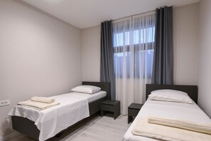 A hotel room with two single beds, a small bedside table, a nightstand, and a large window with sheer curtains. - 2-Bedroom Holiday Apartment with Pool (Orebic)