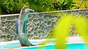 Ein Pool mit einer Steinmauer und üppigem Grün im Hintergrund.