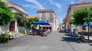 A street with outdoor seating, stone buildings, and a clear blue sky.