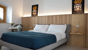 Une chambre moderne avec un grand lit, une tête de lit en bois et deux tableaux accrochés au mur.