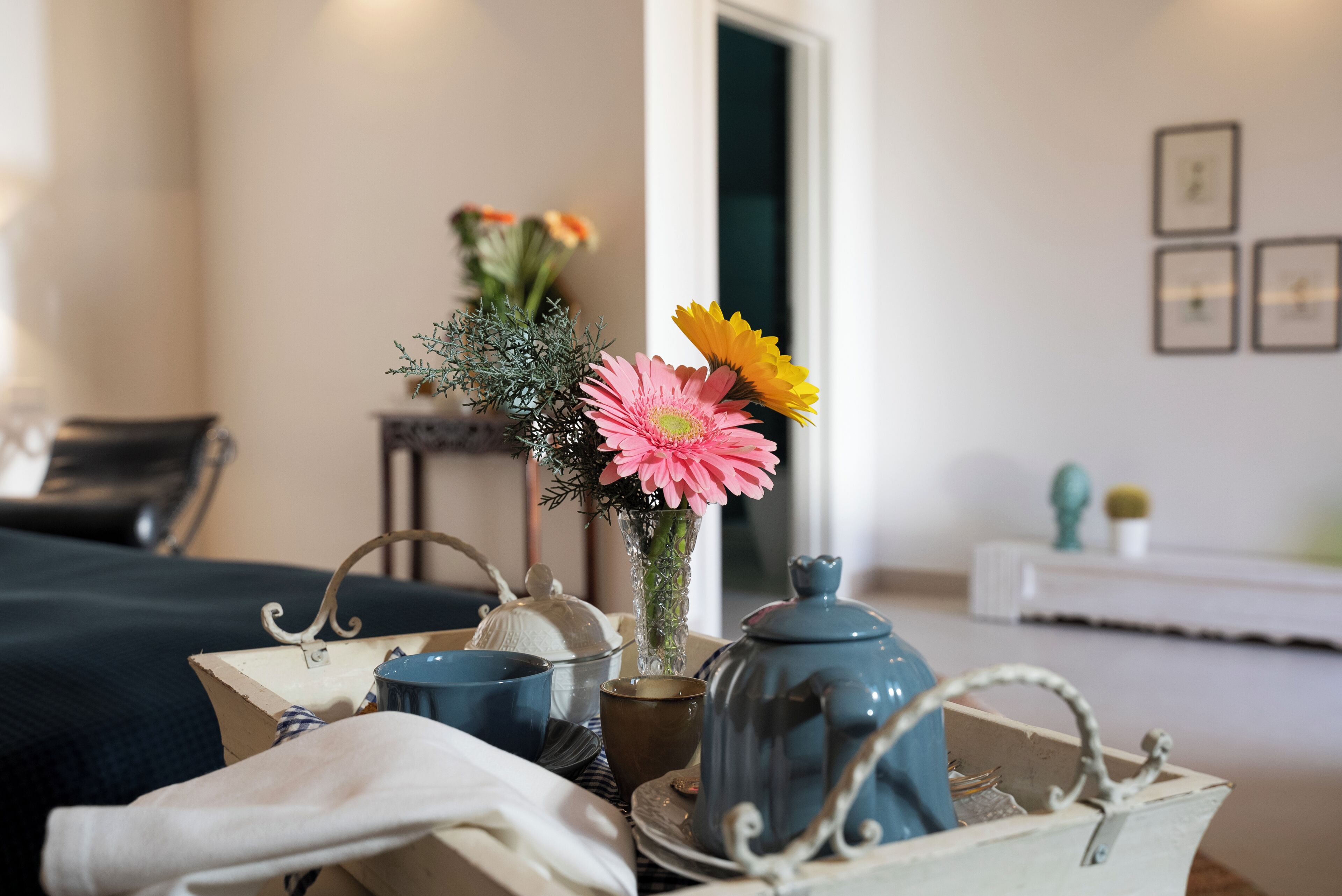 Ein Tisch mit einem Teekessel, Tassen und einer Vase mit Blumen.