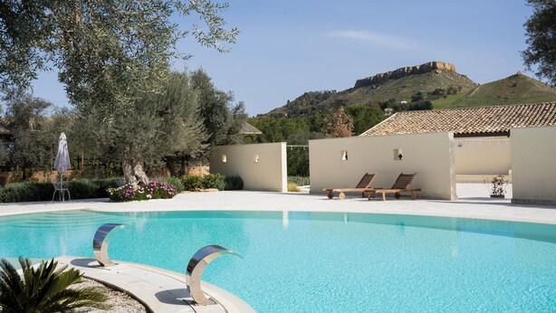 Une piscine avec des chaises longues et une vue sur une colline.