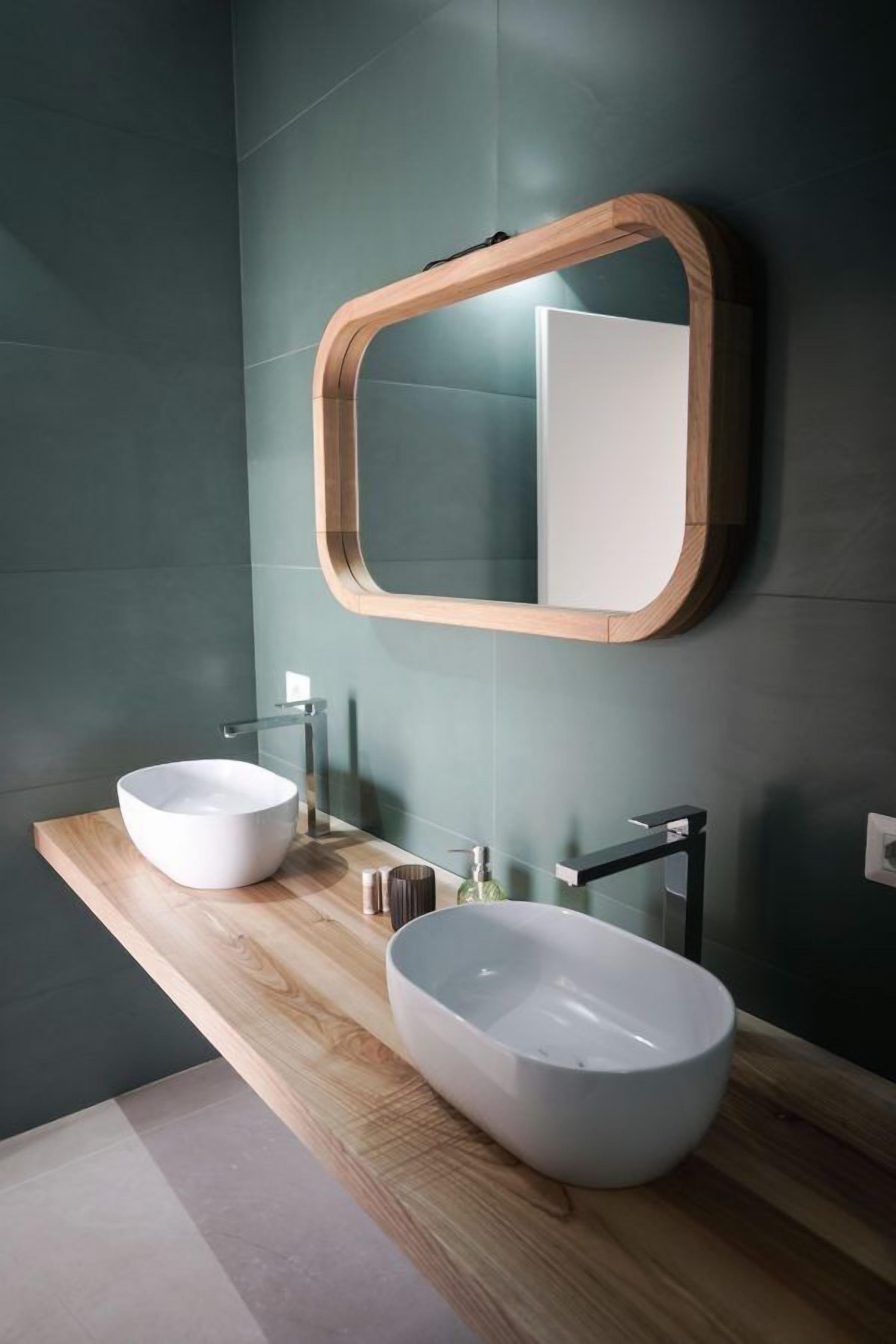 Une salle de bain moderne avec deux grands lavabos blancs, un meuble-lavabo en bois et un miroir avec un cadre en bois.
