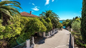A residential street lined with lush greenery and a house with a red-tiled roof. - Great Holiday Home very close to the sea and main beach Trstenica (Orebic)