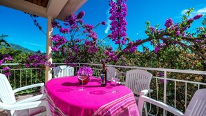 A covered outdoor seating area with a table set for two, surrounded by white chairs, under a canopy of purple bougainvillea flowers. - Great Holiday Home very close to the sea and main beach Trstenica (Orebic)