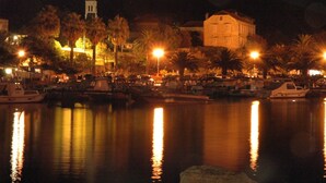 A marina at night with boats docked, a church with a bell tower, and a large building with warm lighting. - Charming Studio Apartment Near the Sea (Orebic)
