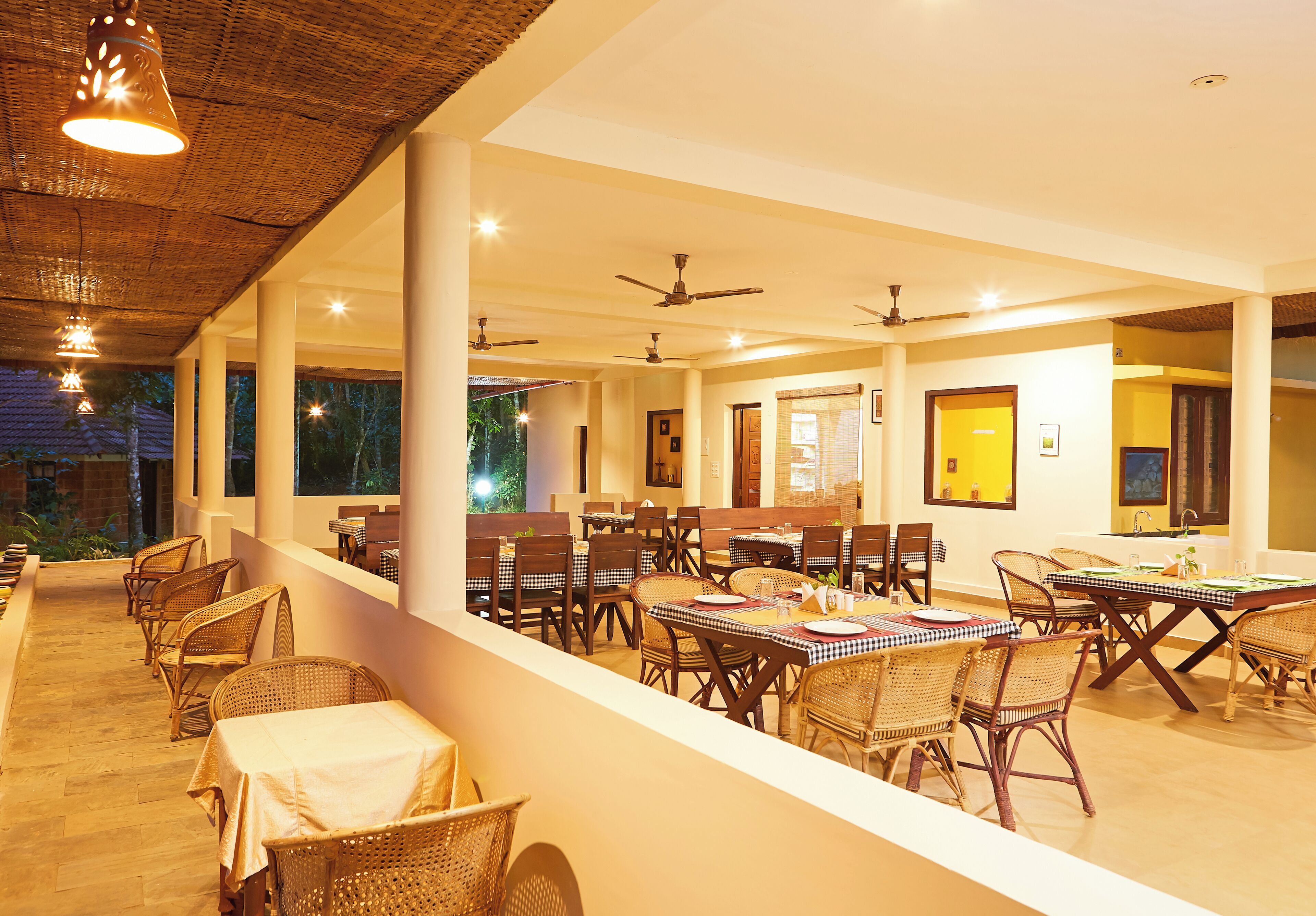 A restaurant with outdoor seating, ceiling fans, and a view of the outdoors.