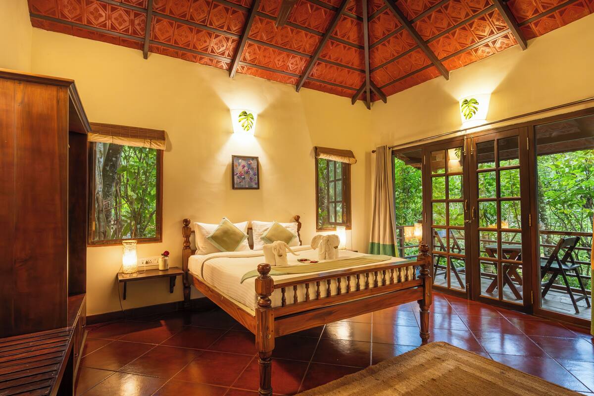 A spacious bedroom with a large bed, a wooden headboard, and a view of the outdoors through large sliding doors.