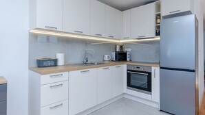 Eine moderne Küche mit weißen Schränken, einem Edelstahl-Kühlschrank, einer Mikrowelle und einem Einbauofen.