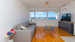 Ein modernes Wohnzimmer mit einem grauen Sofa, einem kleinen Tisch und einem Fernseher auf einer Kommode.