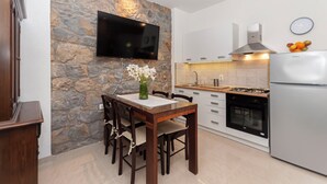 Una cocina moderna con pared de piedra, un televisor de pantalla plana, una mesa de comedor con sillas, un refrigerador y una estufa.
