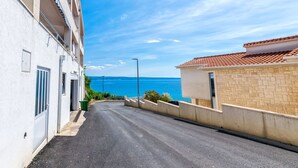 Una calle estrecha con un edificio a la izquierda y vista al mar a la derecha.