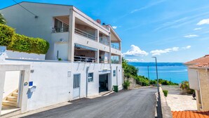Un edificio de dos pisos con un balcón, una escalera y vista al mar.