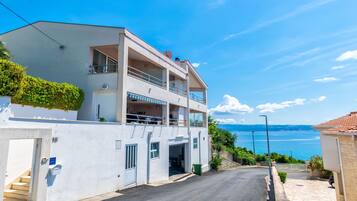 A two-story building with a balcony, a staircase, and a view of the sea.