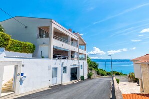 Un immeuble de deux étages doté d’un balcon, d’un escalier et offrant une vue sur la mer.