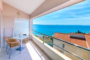 Un balcon avec une table et des chaises, une vue sur la mer et un sol carrelé.