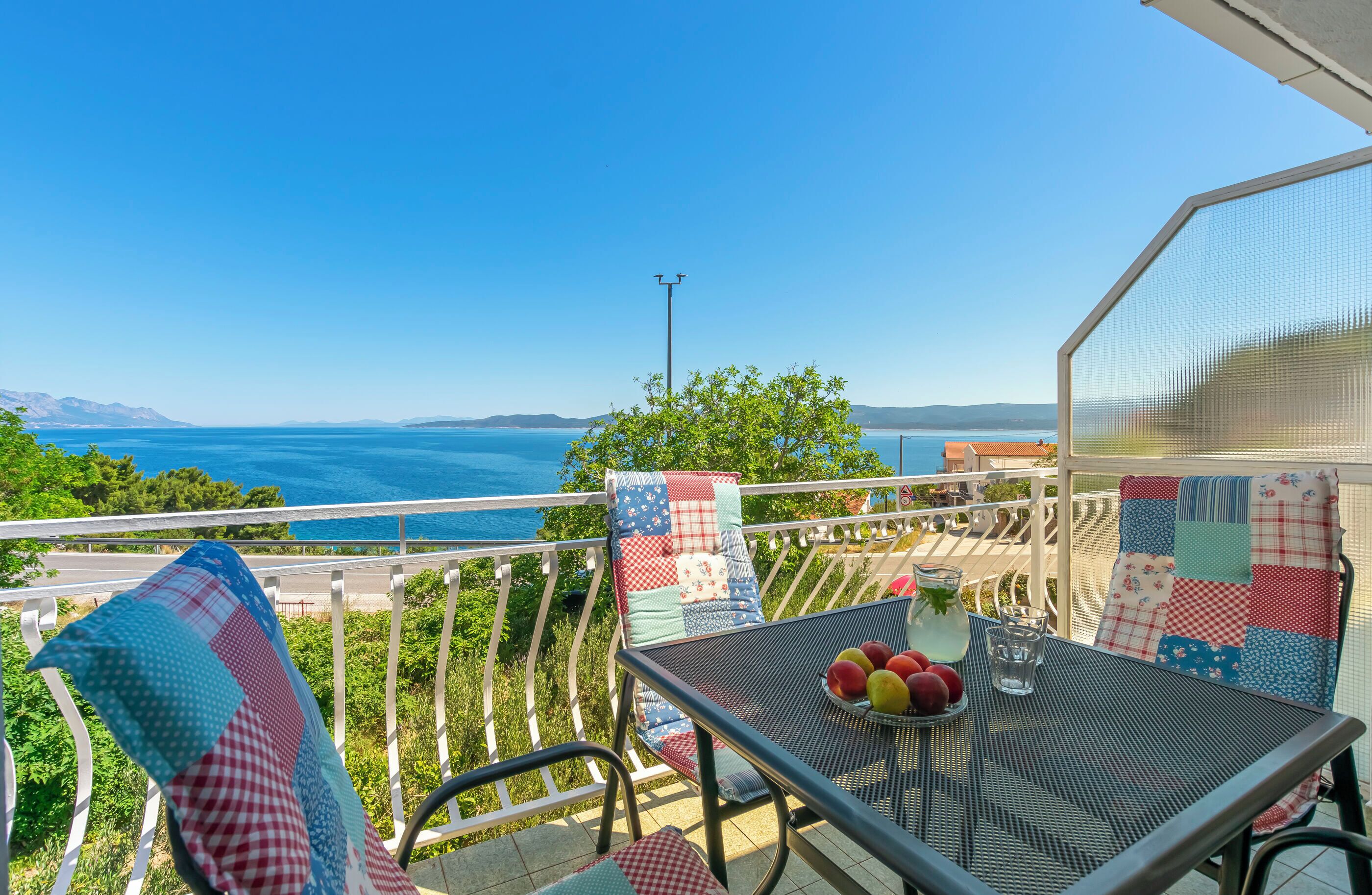 A balcony with a table, chairs, and a view of the sea.