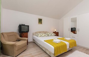 Une chambre à coucher avec un lit, une chaise, une télévision, une armoire et un tableau au mur.