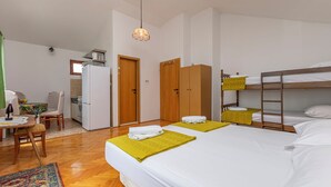 Une chambre d’hôtel avec deux lits, un bureau, une chaise, un réfrigérateur et des armoires en bois.