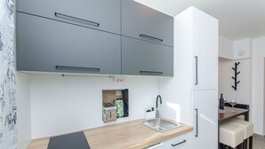A modern kitchen with grey cabinets, a wooden countertop, and a built-in coffee machine. - Apartment Lapis (Split)