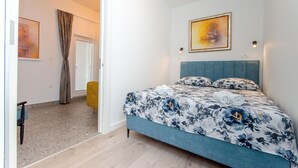 A bedroom with a bed, a headboard, a painting, and a door. - Apartment Lapis (Split)
