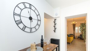 A dining area with a wooden table, a large wall clock, and a modern chandelier. - Apartment Lapis (Split)