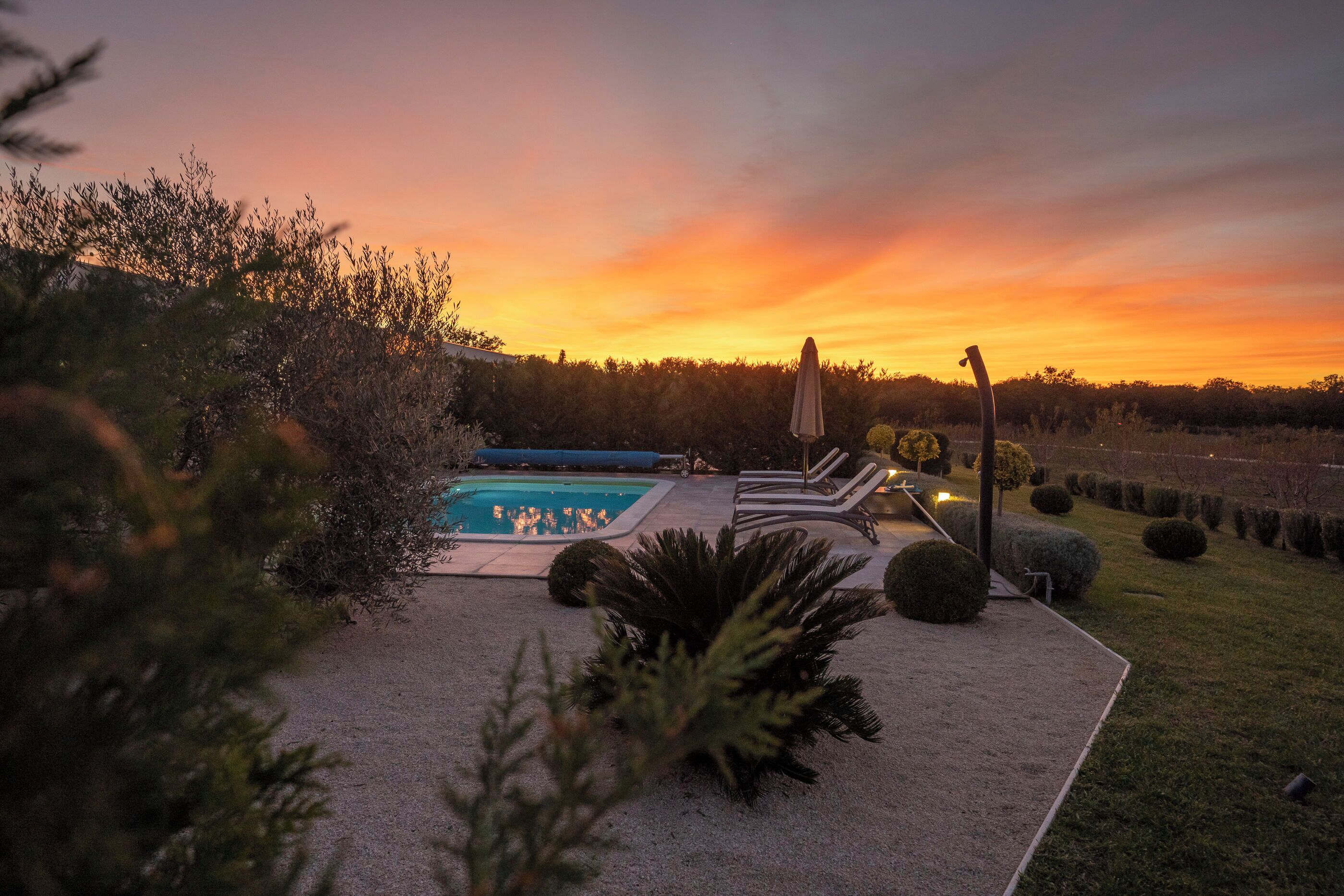 Ein Poolbereich mit Liegestühlen und Blick auf einen Sonnenuntergang.