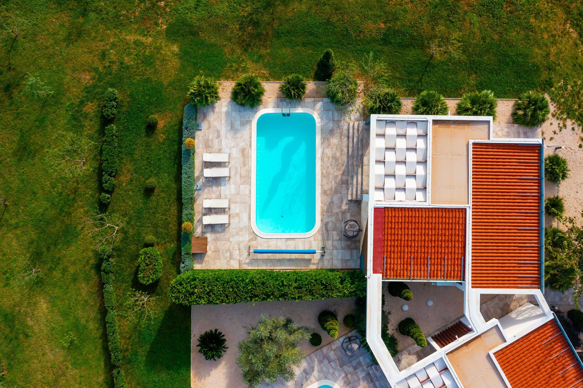 An aerial view of a property with a swimming pool, outdoor seating, and a covered patio area.