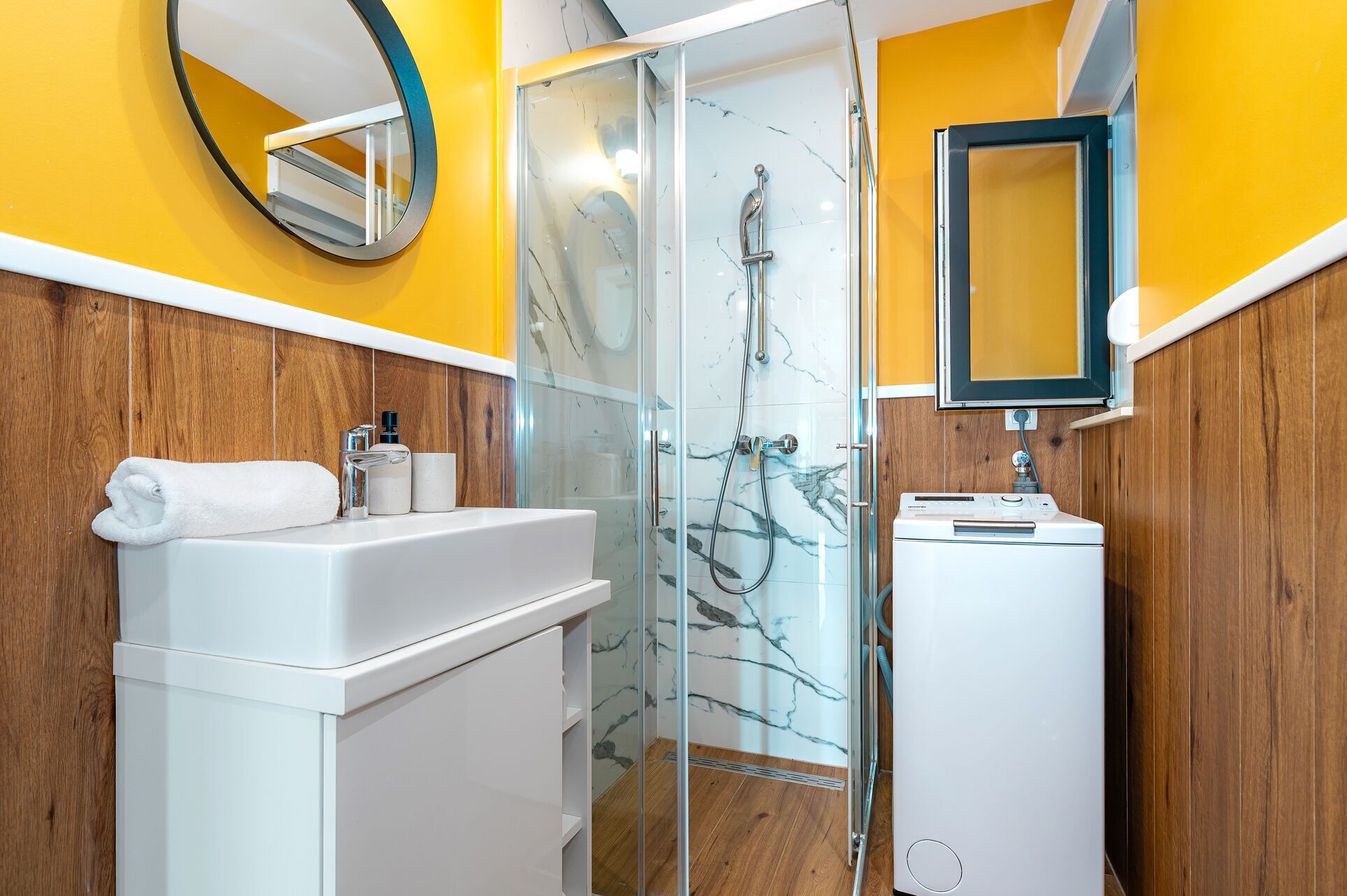 A modern bathroom with a glass-enclosed shower, a white sink, and a mirror.