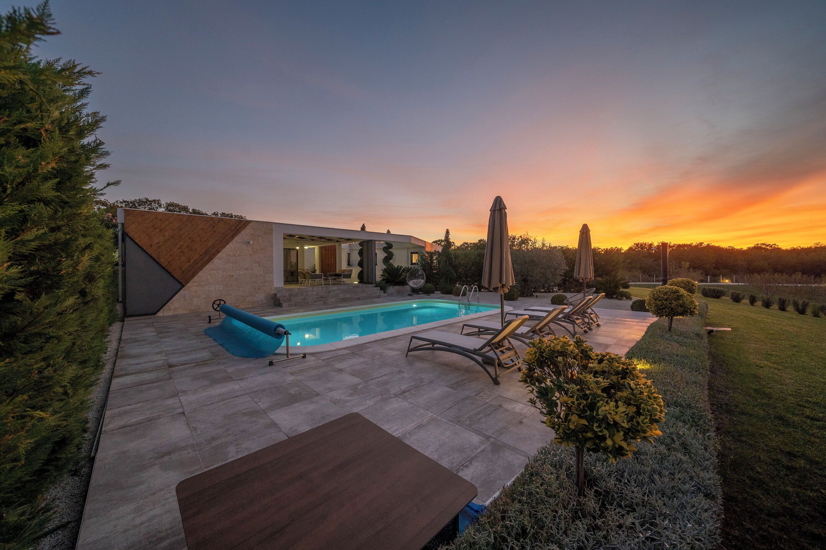 A modern house with a swimming pool, outdoor furniture, and a well-maintained garden.