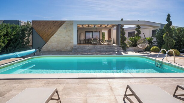 A swimming pool with a pergola, lounge chairs, and a patio area. - Villa Royal Green Two (Nin)