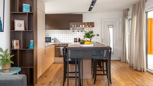 A modern kitchen with wooden cabinets, a dining table, and a potted plant. - Villa Royal Green Two (Nin)