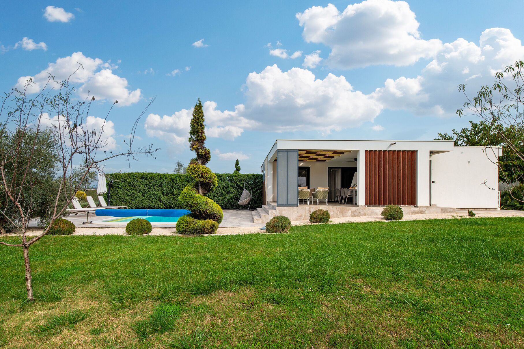 A modern house with a pool, outdoor seating, and a well-maintained garden.