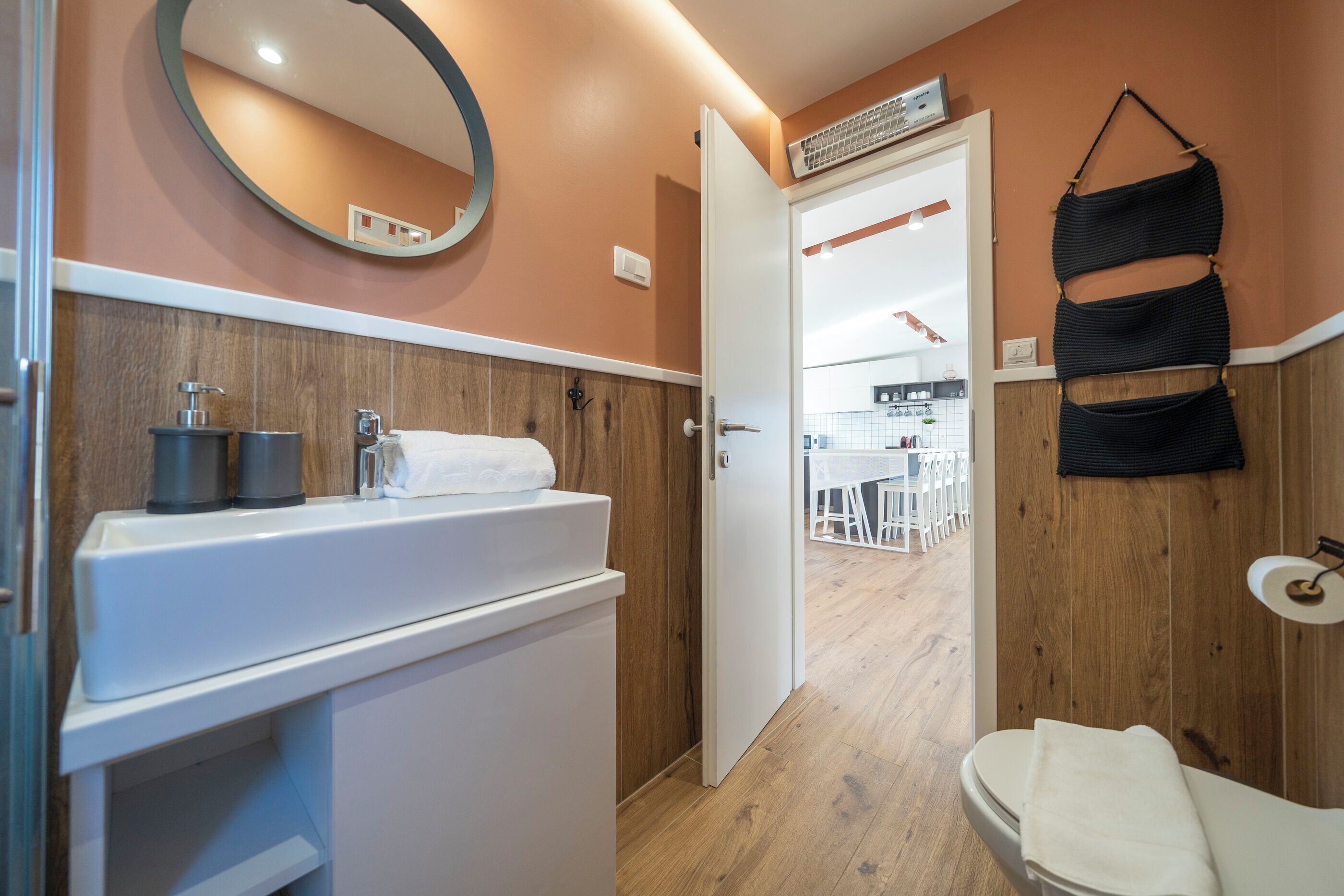 Une salle de bain avec un meuble-lavabo en bois, un miroir et un porte-serviettes.