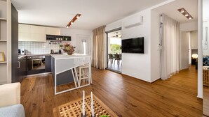A modern kitchen with white cabinets, a dining area with a white table, and a TV mounted on the wall.