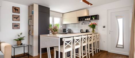 Una cocina moderna con una isla central, taburetes de bar y un comedor.