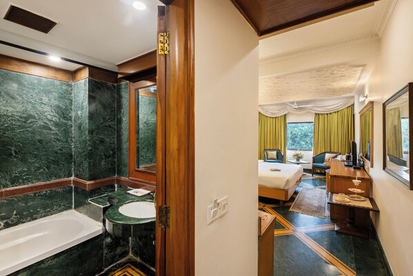 A hotel room with a marble bathroom, a bed with a view, and a desk with a television. - Hotel Kwality Regency (Chandigarh)