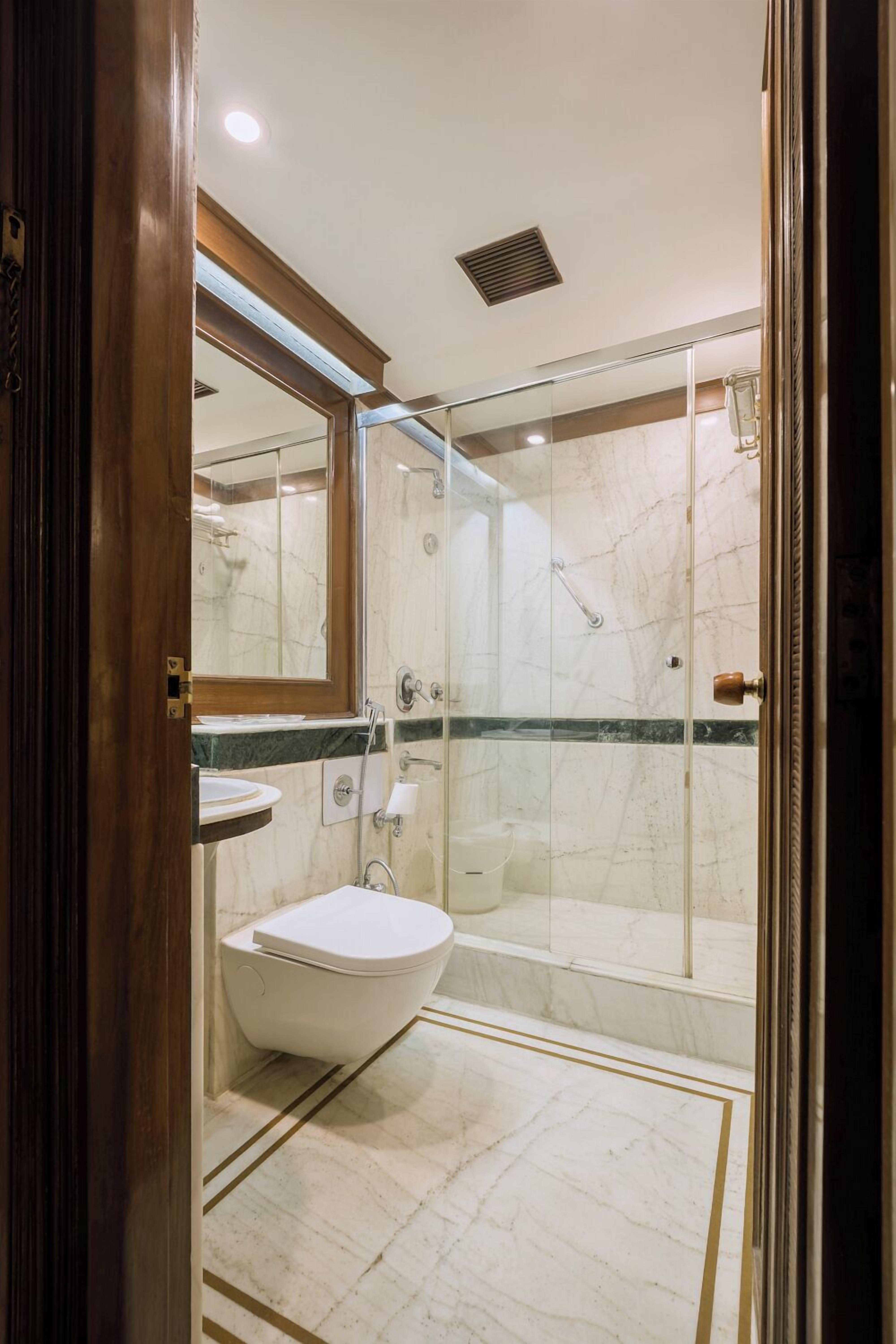 A modern bathroom with a glass-enclosed shower, a freestanding sink, and a marble-tiled floor.