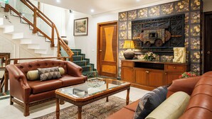A spacious living room with a leather sofa, a glass coffee table, and a staircase leading to an upper floor. - Hotel Kwality Regency (Chandigarh)