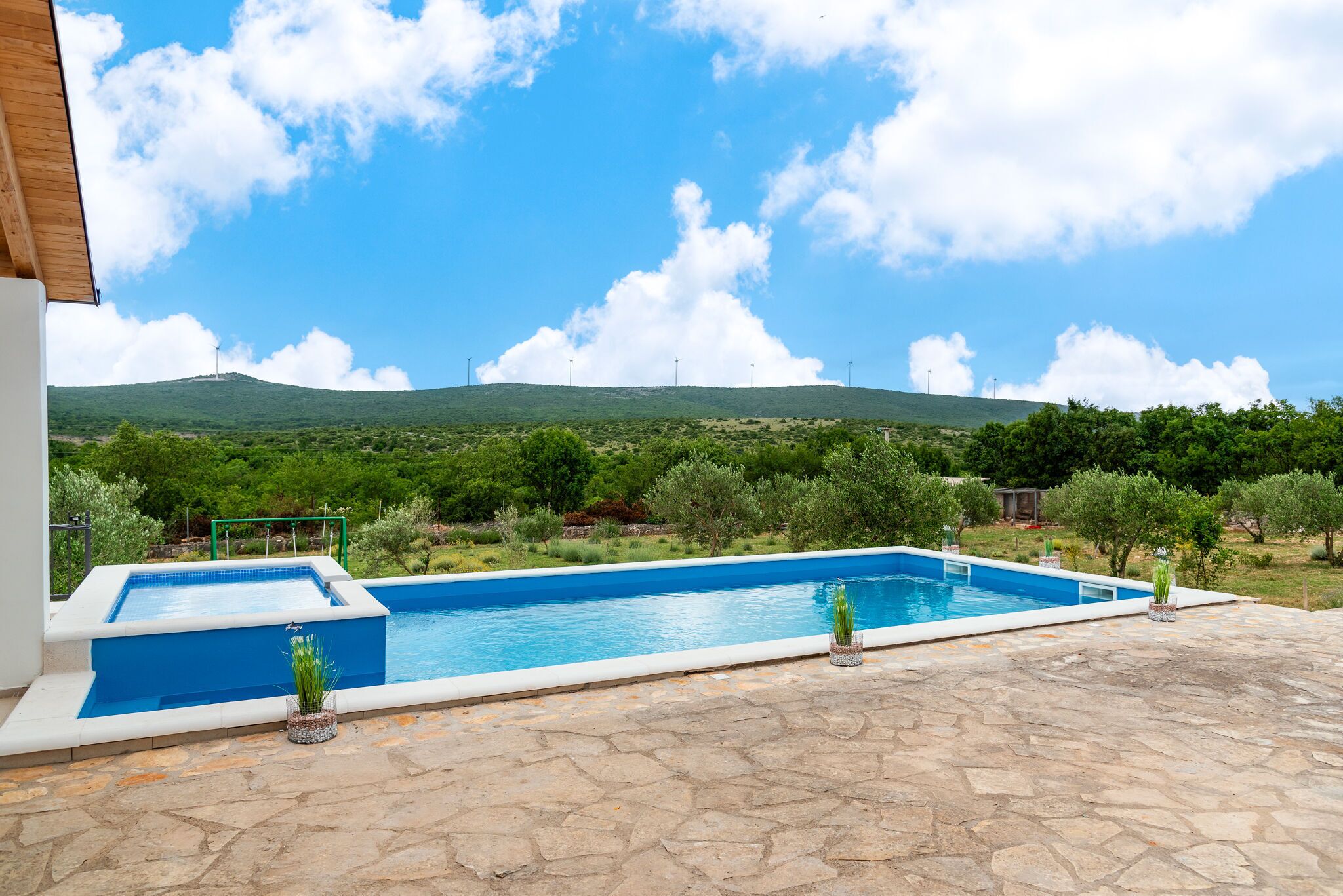 A swimming pool with a view of a green landscape and a hill in the background.