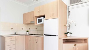 Une cuisine avec des meubles en bois, un four à micro-ondes, un réfrigérateur et une plante en pot.