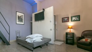 A bedroom with a bed, a TV mounted on the wall, a chair, and a lamp. - Spacious Studio in via Sammartini 33 (Milan)