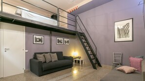 A compact studio apartment with a bunk bed, a sofa, a small table with a lamp, and framed pictures on the walls. - Spacious Studio in via Sammartini 33 (Milan)