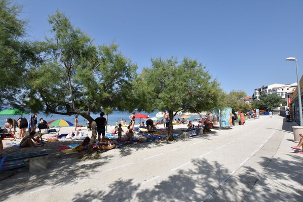 A beachside area with people sunbathing, umbrellas, and beach chairs. - Apartment Panorama (Dugi rat)