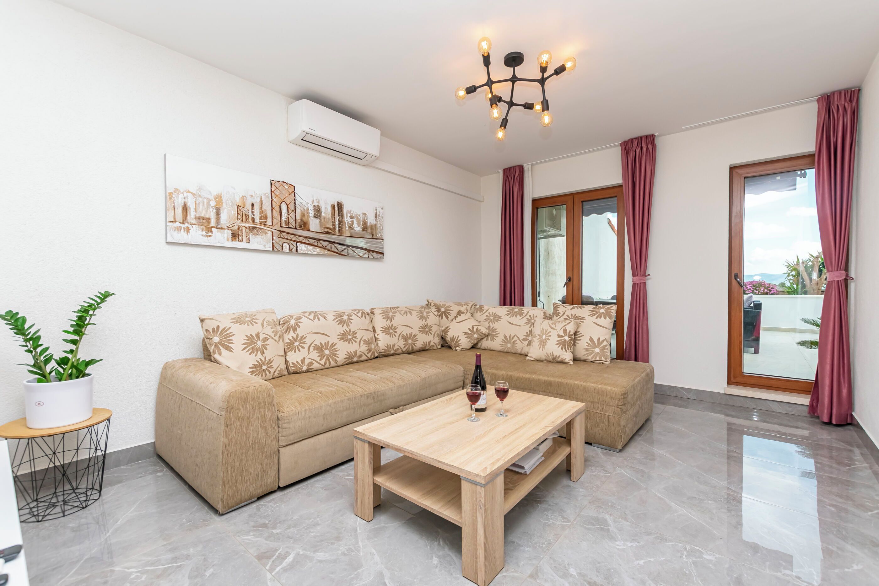 Ein modernes Wohnzimmer mit einem beigefarbenen Ecksofa, einem Holztisch und einer Topfpflanze.