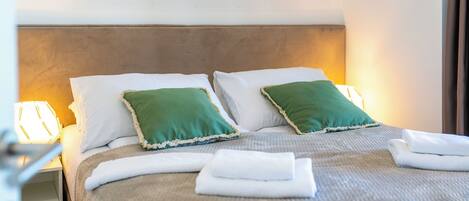 A neatly made bed with two pillows, a headboard, and a bedside lamp.