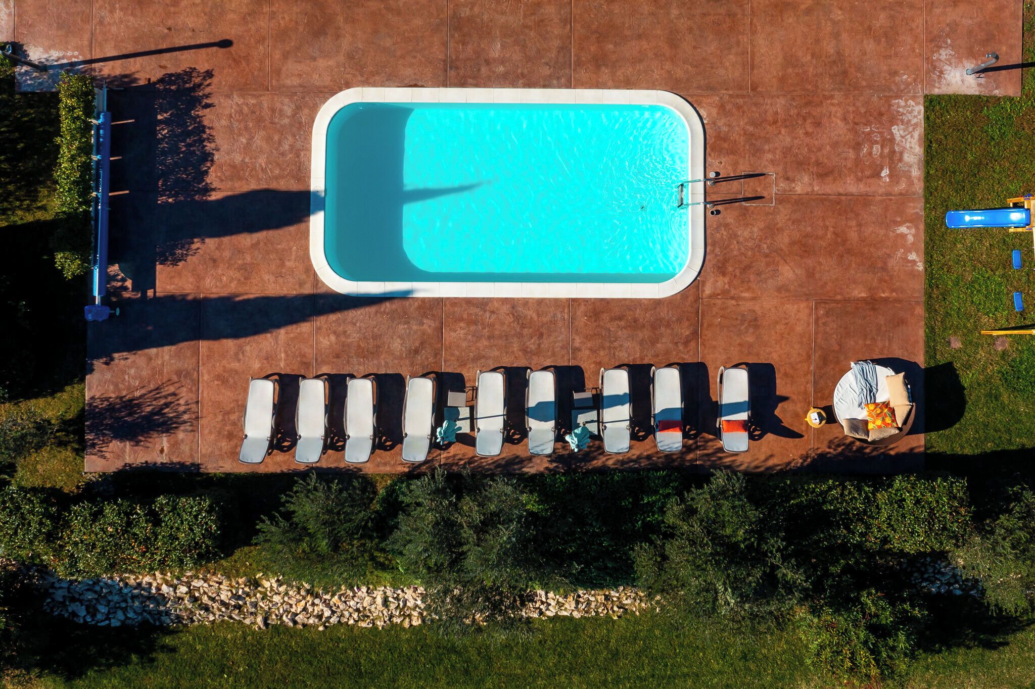An aerial view of a swimming pool with lounge chairs and a small boat.